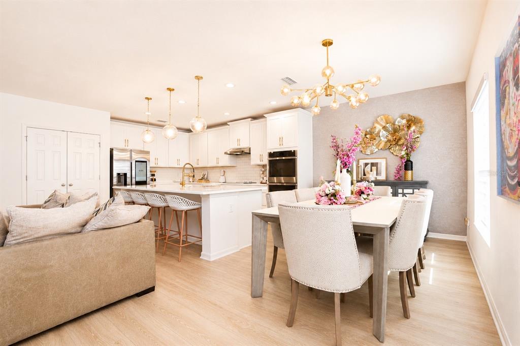 A bright open-concept kitchen and dining area with white cabinetry, a large island, and chandelier — 9385 LA SALLE STREET, GROVELAND, FL