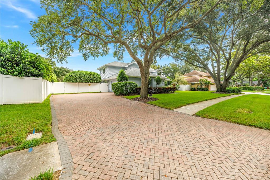 A light blue two-story house with a brick paver driveway and large mature oak trees — 12383 WINDTREE BOULEVARD, SEMINOLE, FL