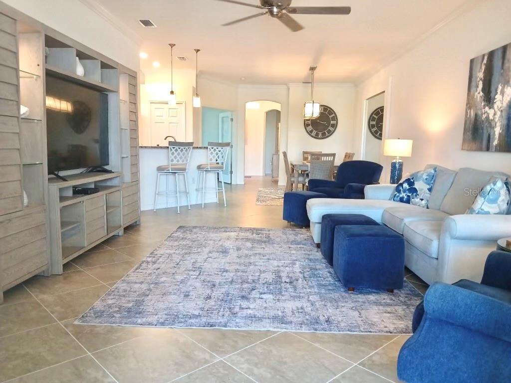 An open-concept living room features a large area rug, blue furniture, and a kitchen island — 12568 FELICE DRIVE, VENICE, FL