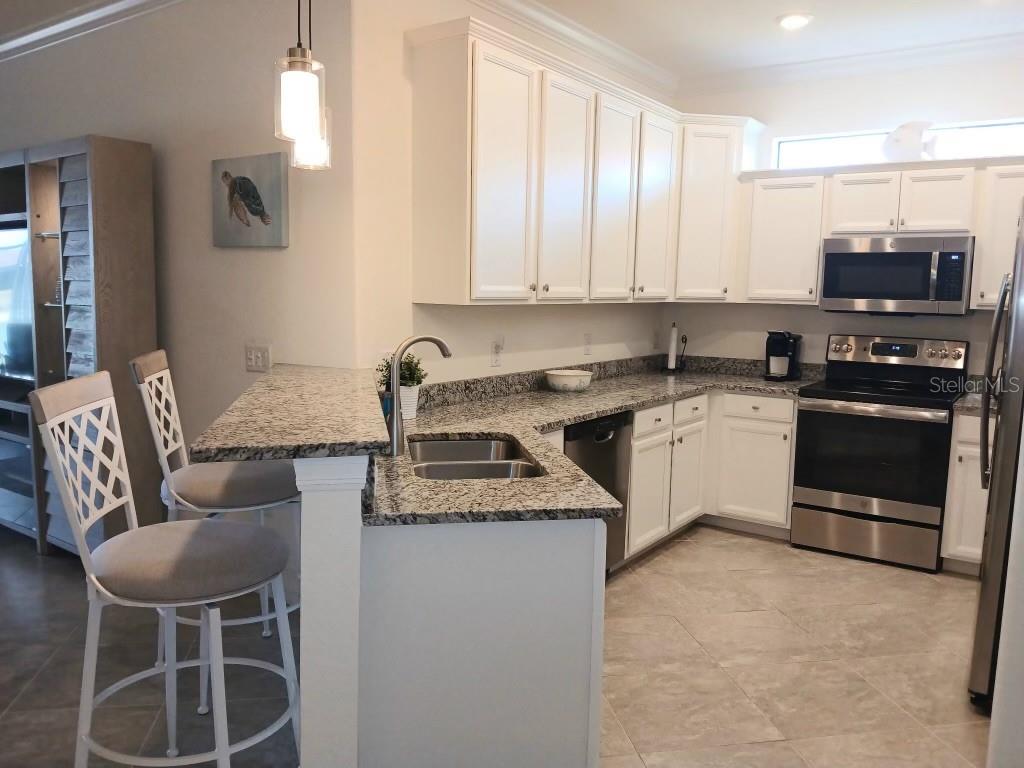 A kitchen features white cabinets, granite countertops, stainless steel appliances, and a breakfast bar — 12568 FELICE DRIVE, VENICE, FL