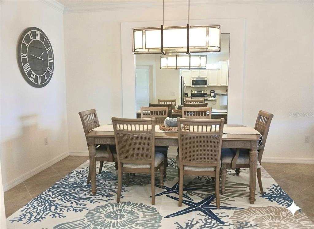 A dining room features a wooden table, six chairs, a patterned rug, and a large mirror — 12568 FELICE DRIVE, VENICE, FL