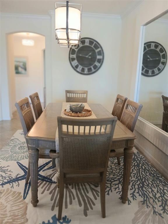 A dining room features a wooden table, six chairs, a coastal rug, and a wall clock — 12568 FELICE DRIVE, VENICE, FL