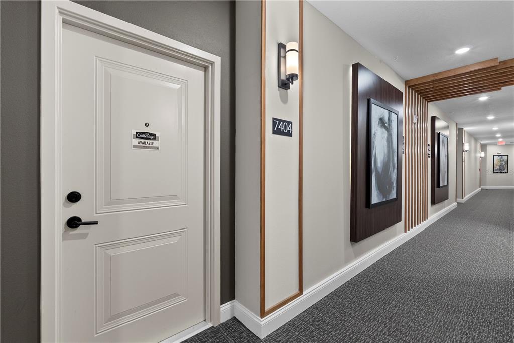 A hallway with a white door, a room number sign, and framed wall art — 7545 LAUREATE BOULEVARD UNIT 7404, ORLANDO, FL
