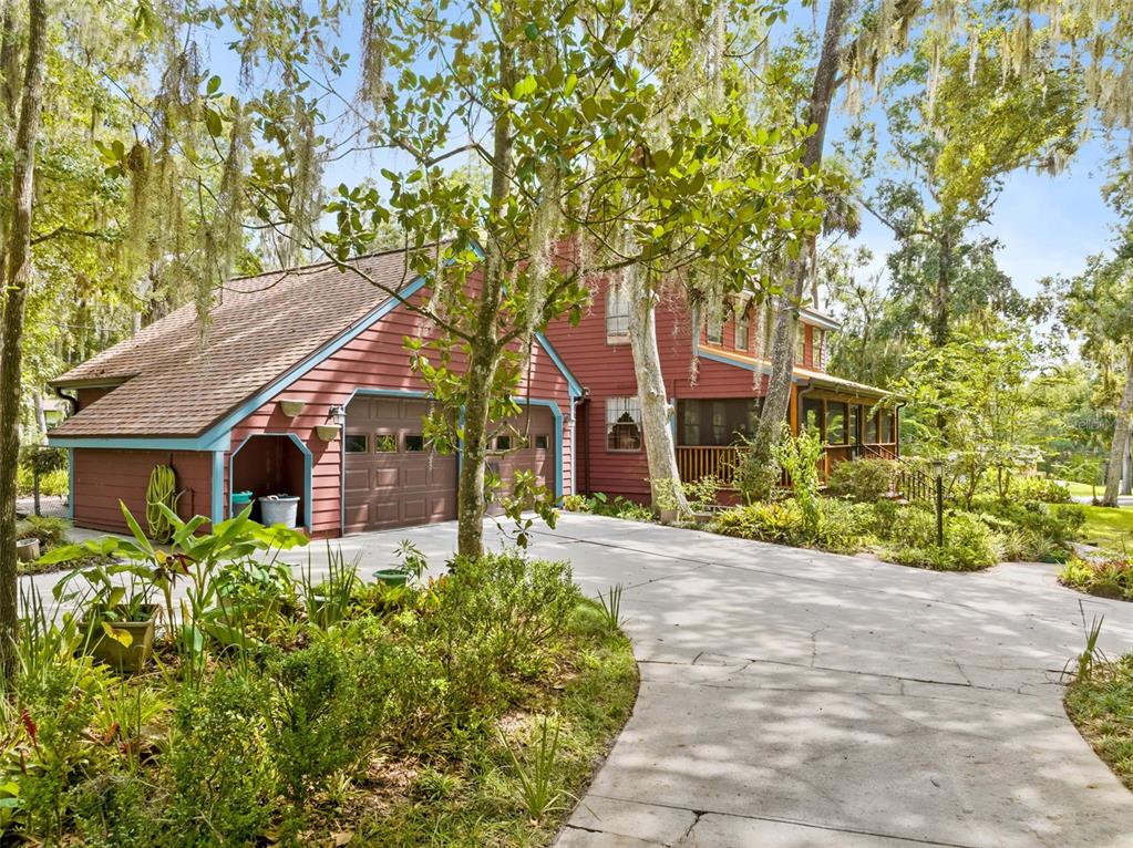 A two-story red house with a two-car garage and a screened porch sits among trees — 20485 YONTZ ROAD, BROOKSVILLE, FL