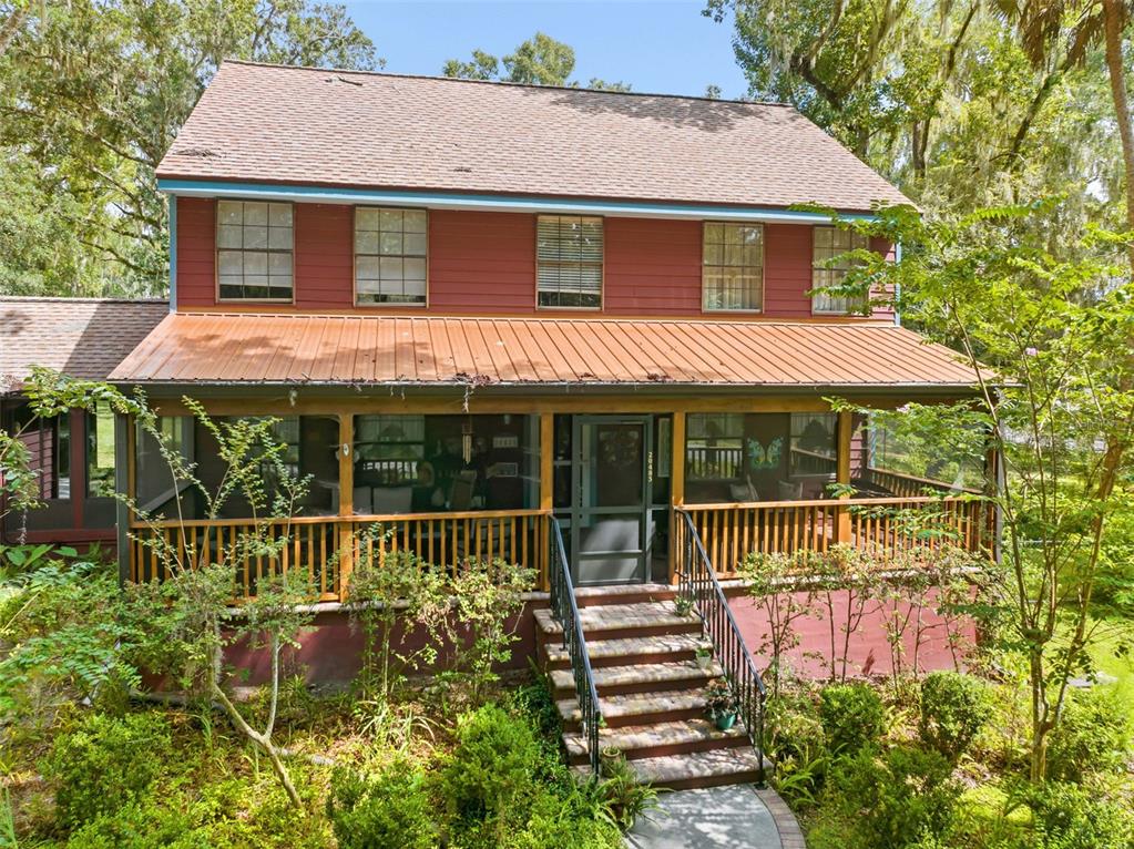 A two-story house with red siding, a metal porch roof, and brick front steps — 20485 YONTZ ROAD, BROOKSVILLE, FL
