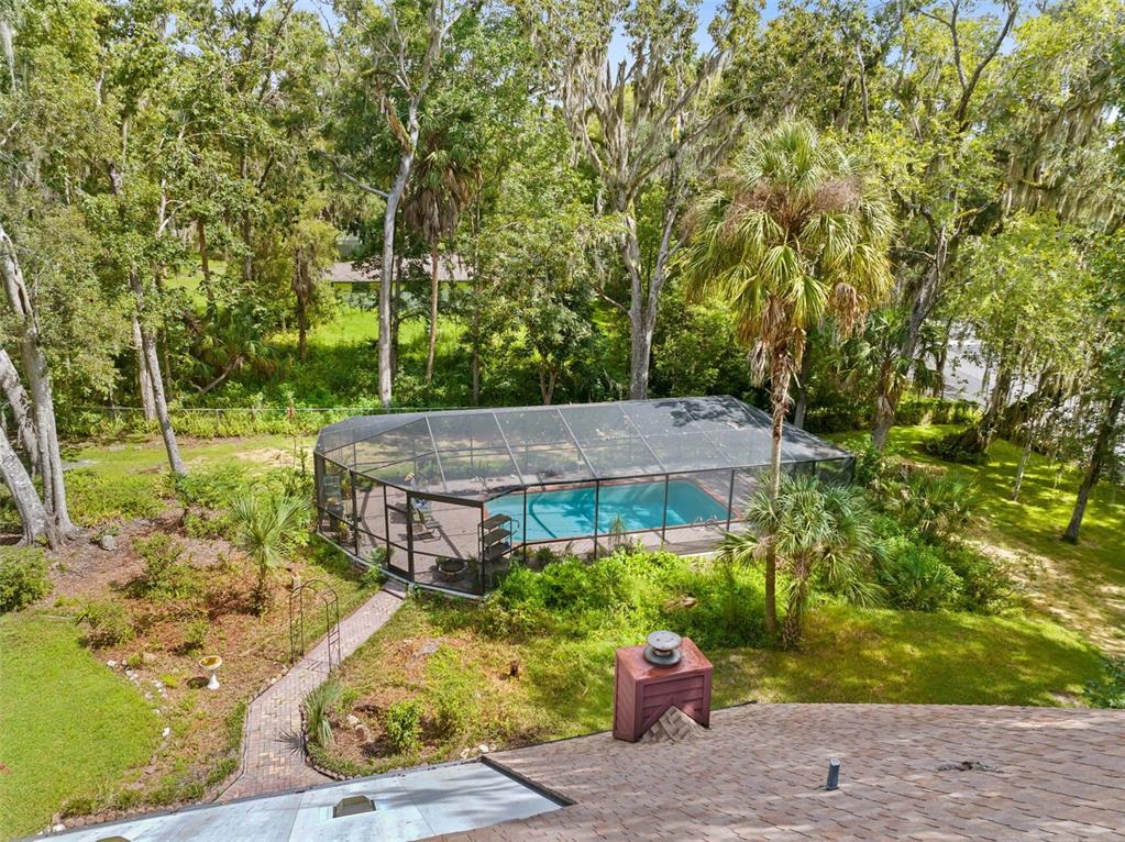 An elevated view of a backyard featuring a screened-in swimming pool and a brick walkway — 20485 YONTZ ROAD, BROOKSVILLE, FL