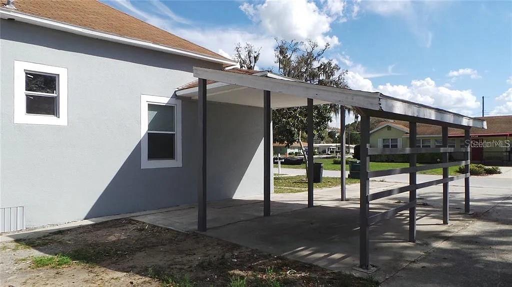 A gray house features a concrete driveway covered by an attached wooden carport — 707 AVENUE B SW UNIT B, WINTER HAVEN, FL