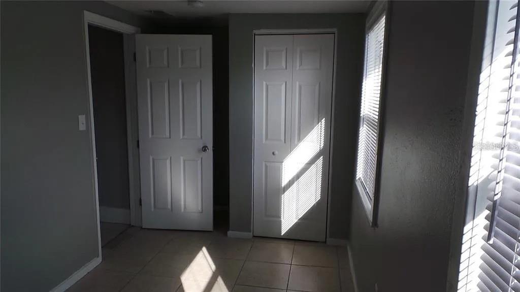 A room with gray walls, tiled flooring, a standard door, and a white bi-fold closet — 707 AVENUE B SW UNIT B, WINTER HAVEN, FL