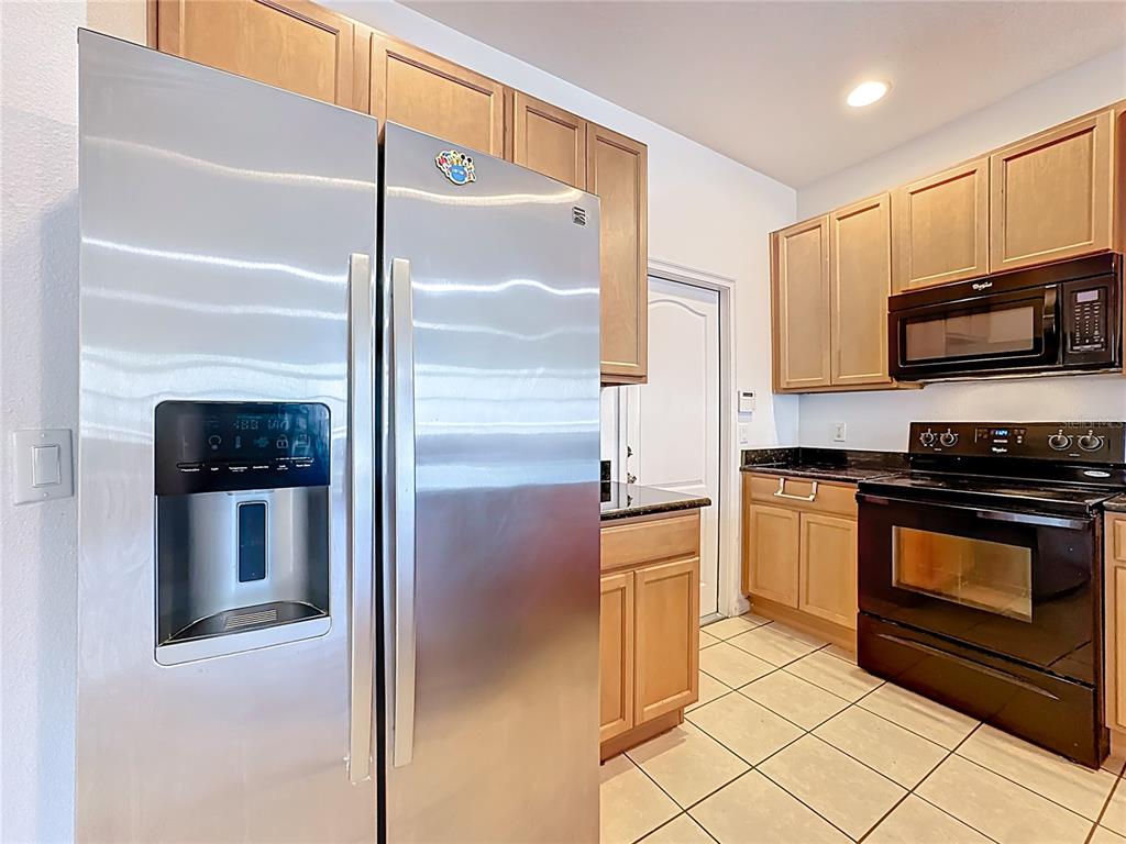 A kitchen features stainless steel appliances, light wood cabinets, and light-colored tile flooring — 1991 SWITCH GRASS CIRCLE, OCOEE, FL