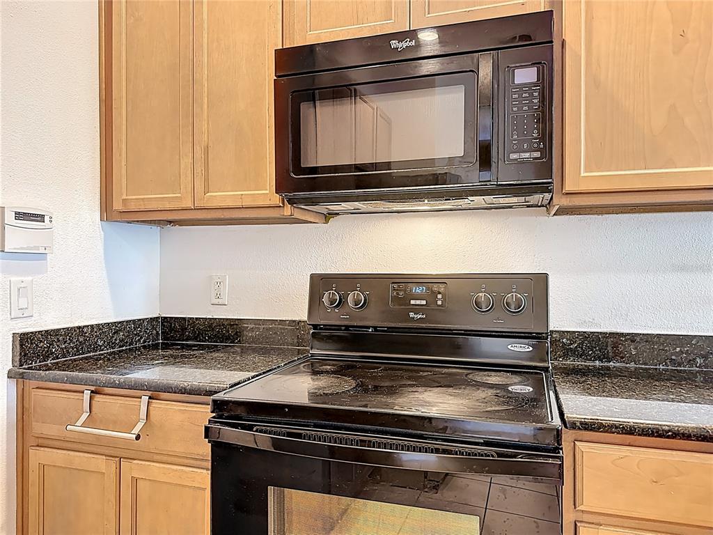 A kitchen features light wood cabinets, a black electric stove, and a black microwave — 1991 SWITCH GRASS CIRCLE, OCOEE, FL