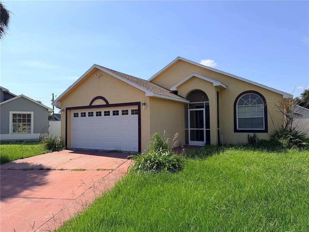 A single-story house with a yellow stucco exterior, a two-car garage, and an arched window — 863 COUNTRY CROSSING COURT, KISSIMMEE, FL