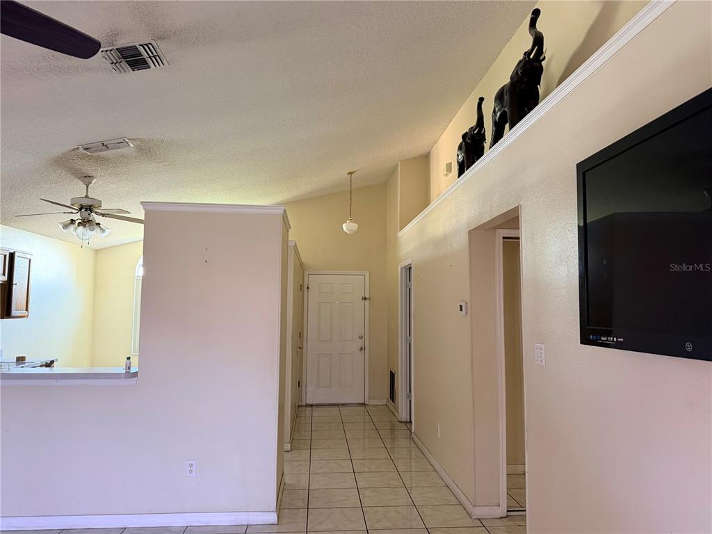 An interior view shows a tiled entryway, a vaulted ceiling, and a kitchen pass-through window — 863 COUNTRY CROSSING COURT, KISSIMMEE, FL
