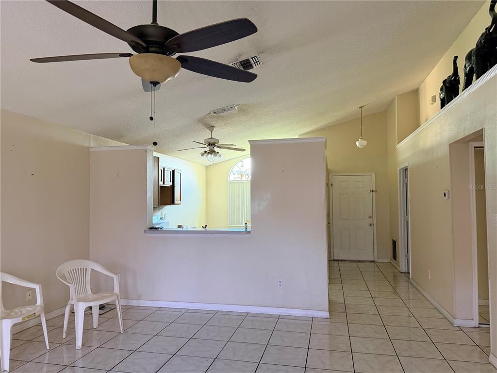 A living room with tile flooring, a ceiling fan, and an open view into the kitchen — 863 COUNTRY CROSSING COURT, KISSIMMEE, FL