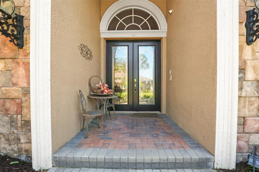 A front entryway features a double glass door, a brick porch, and stone wall accents — 27608 PINE POINT DRIVE, WESLEY CHAPEL, FL