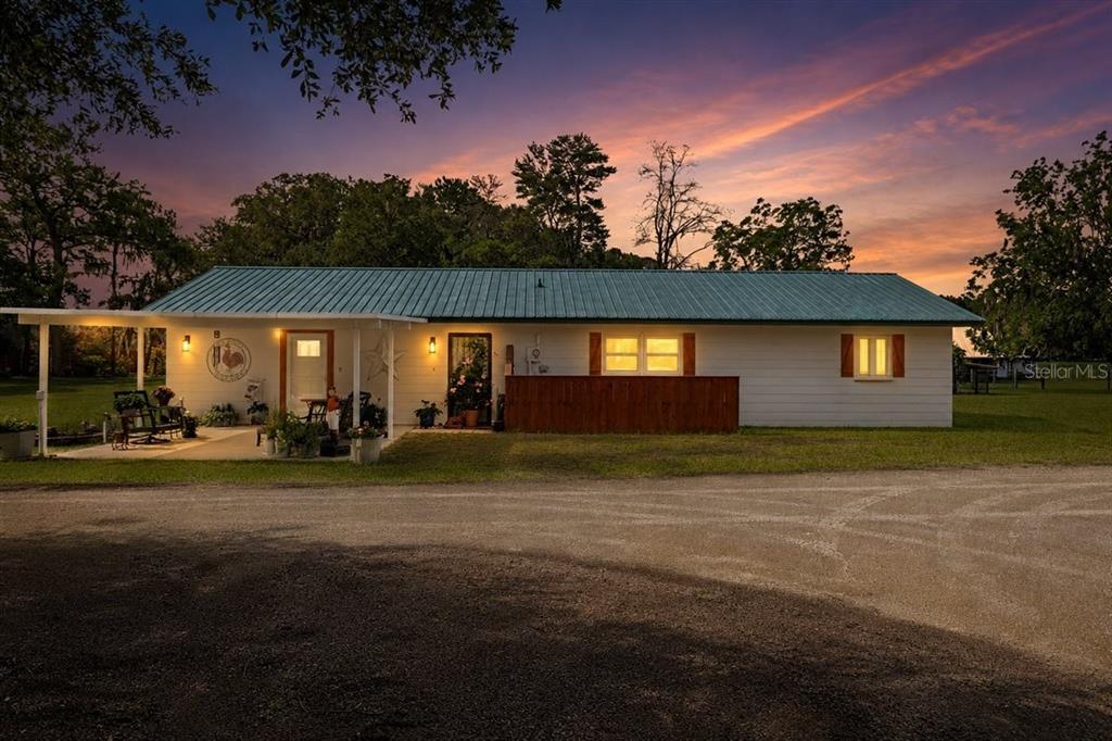 A single-story house with a metal roof and a covered porch at sunset — 3019 SE 90TH AVENUE, NEWBERRY, FL