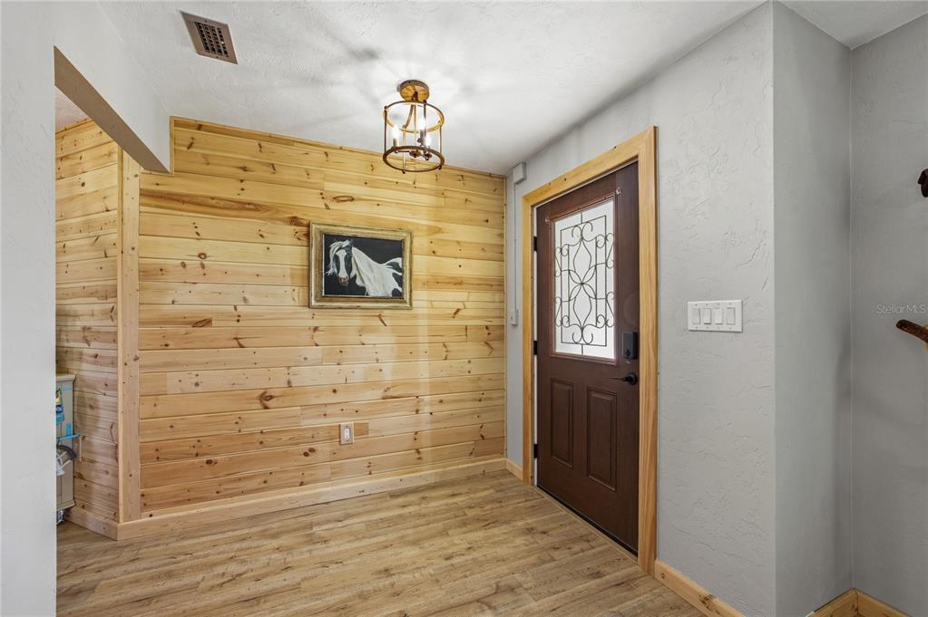 An entryway features wood-paneled walls, a brown front door, and a light fixture — 3019 SE 90TH AVENUE, NEWBERRY, FL
