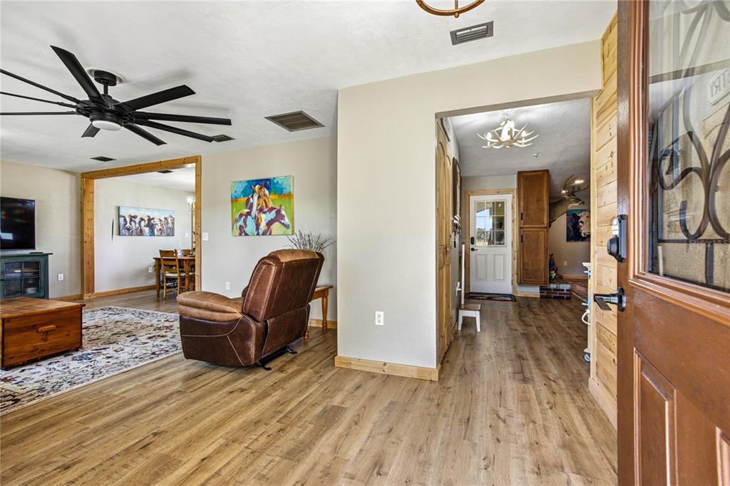 A living room with wood-look flooring, a ceiling fan, and an entryway leading to a foyer — 3019 SE 90TH AVENUE, NEWBERRY, FL