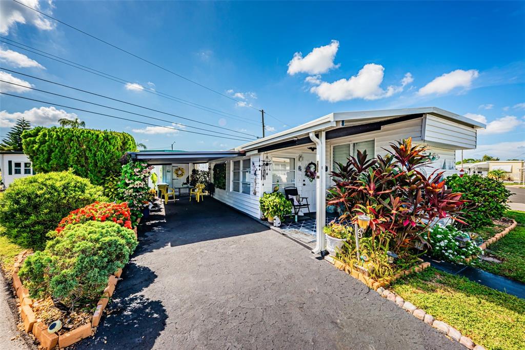 A single-story mobile home features a white exterior, a paved driveway, and landscaped front gardens — 4187 72ND STREET N UNIT 32, ST PETERSBURG, FL