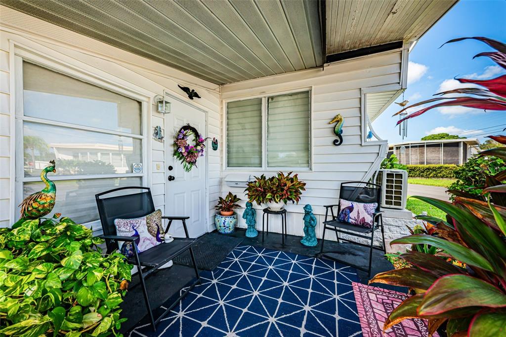 A white house exterior features a covered carport, a small front porch, and potted plants — 4187 72ND STREET N UNIT 32, ST PETERSBURG, FL