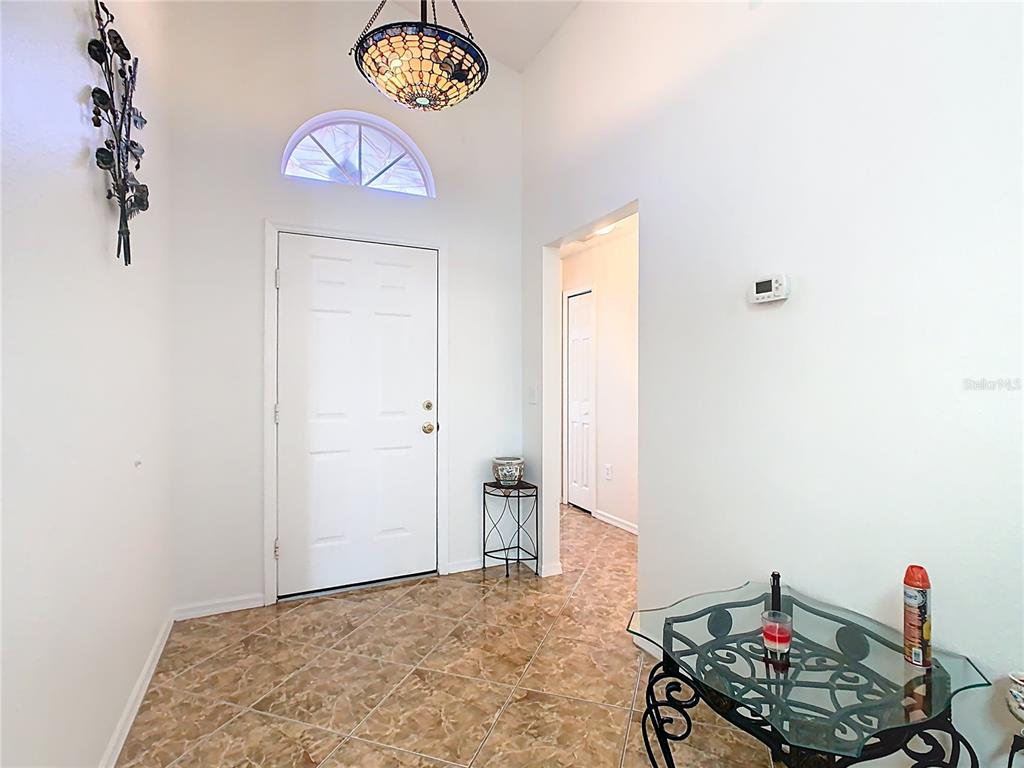 An entryway features tiled floors, a white front door with a transom window, and lighting — 230 HALSTEAD DRIVE, DAVENPORT, FL