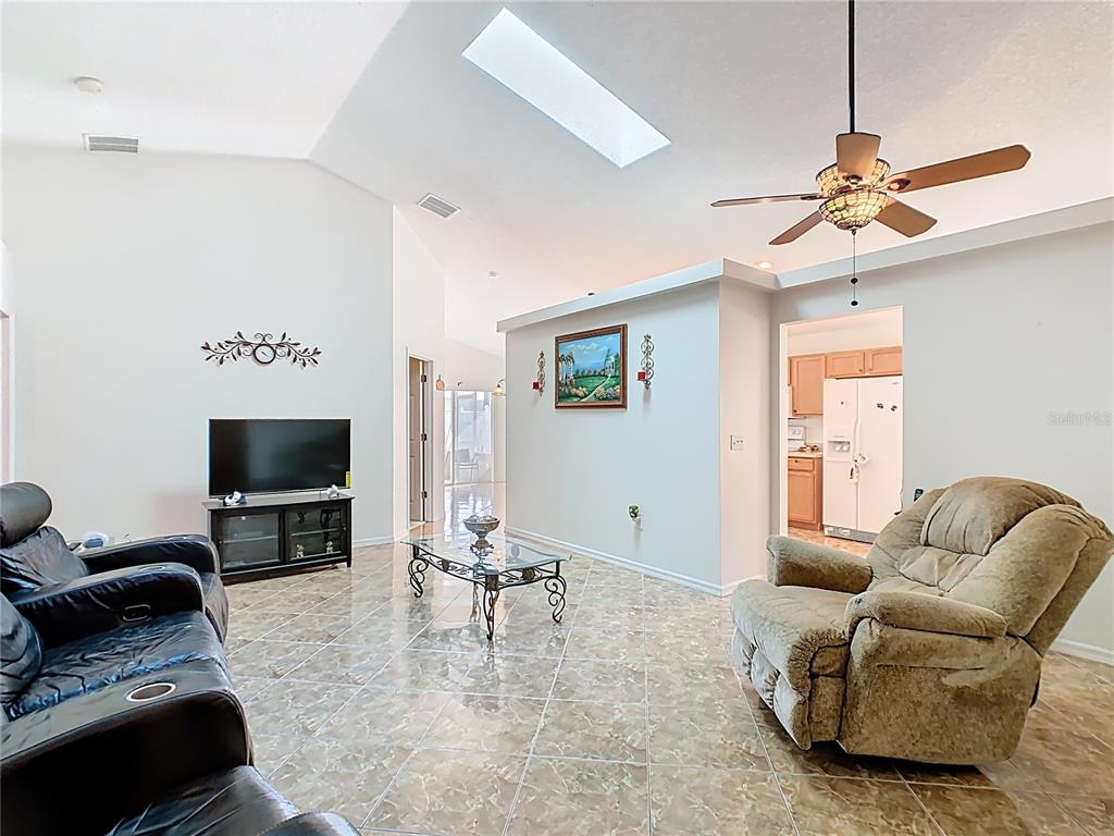 A living room with vaulted ceilings, a skylight, tile flooring, and a ceiling fan — 230 HALSTEAD DRIVE, DAVENPORT, FL