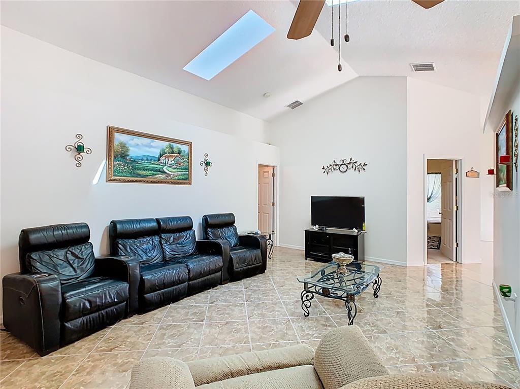 A living room features black leather recliners, a glass coffee table, and a vaulted ceiling — 230 HALSTEAD DRIVE, DAVENPORT, FL