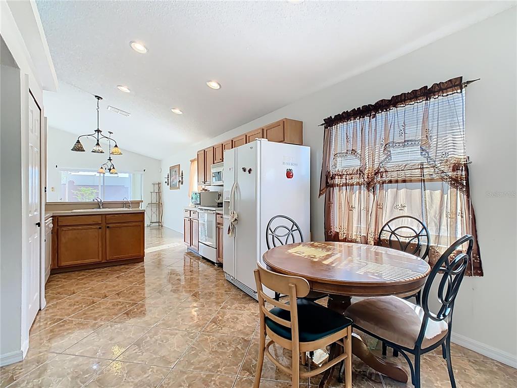 A kitchen and dining area with tile floors, wooden cabinets, and a round table — 230 HALSTEAD DRIVE, DAVENPORT, FL
