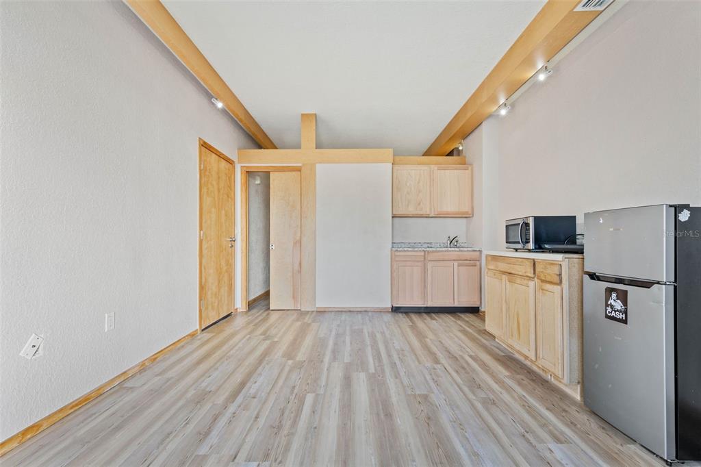 A small kitchenette with light wood cabinets, a microwave, and a refrigerator in a room — 101 PALM HARBOR PARKWAY UNIT C231, PALM COAST, FL