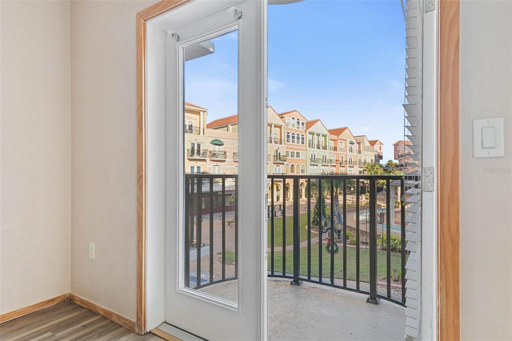 A glass door opens from a room with wood-look flooring to a balcony overlooking buildings — 101 PALM HARBOR PARKWAY UNIT C231, PALM COAST, FL