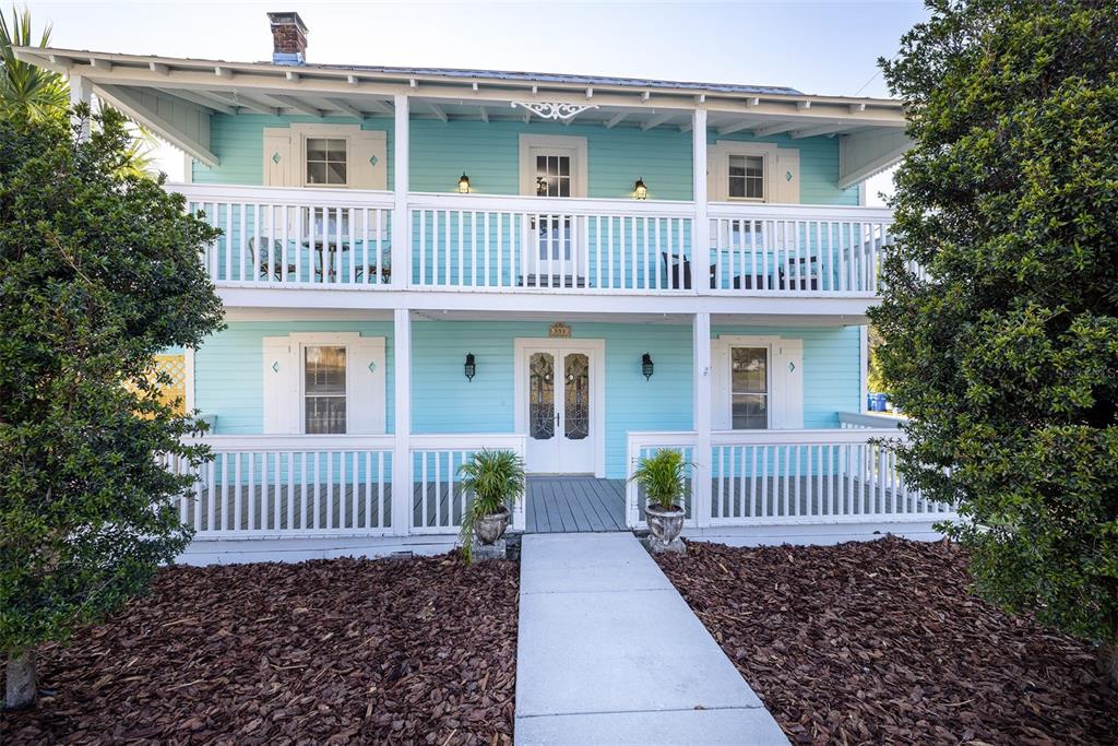 A two-story light blue house with a double-decker porch and a concrete walkway — 551 OMAHA STREET, PALM HARBOR, FL