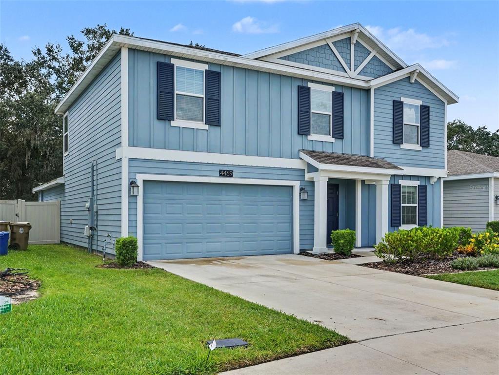 A two-story blue house with a two-car garage and a front porch — 4469 BLUFF OAK LOOP, KISSIMMEE, FL
