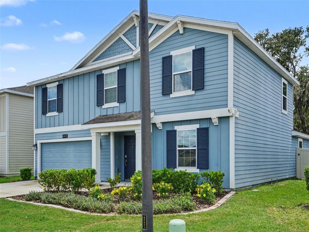 A two-story blue house with white trim, dark shutters, and a front-facing garage — 4469 BLUFF OAK LOOP, KISSIMMEE, FL