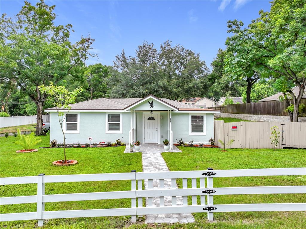 A light green single-story house with a white fence and a stone walkway — 552 B C TERRY ROAD, OCOEE, FL
