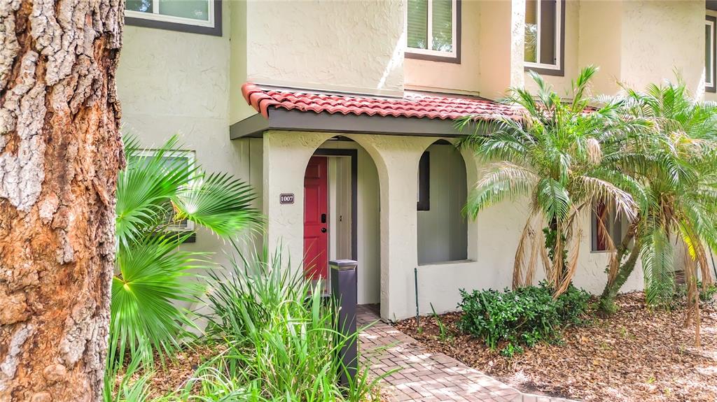 A two-story stucco townhouse with a red front door and a brick walkway — 1007 BASEBALL AND BOARDWALK COURT, KISSIMMEE, FL