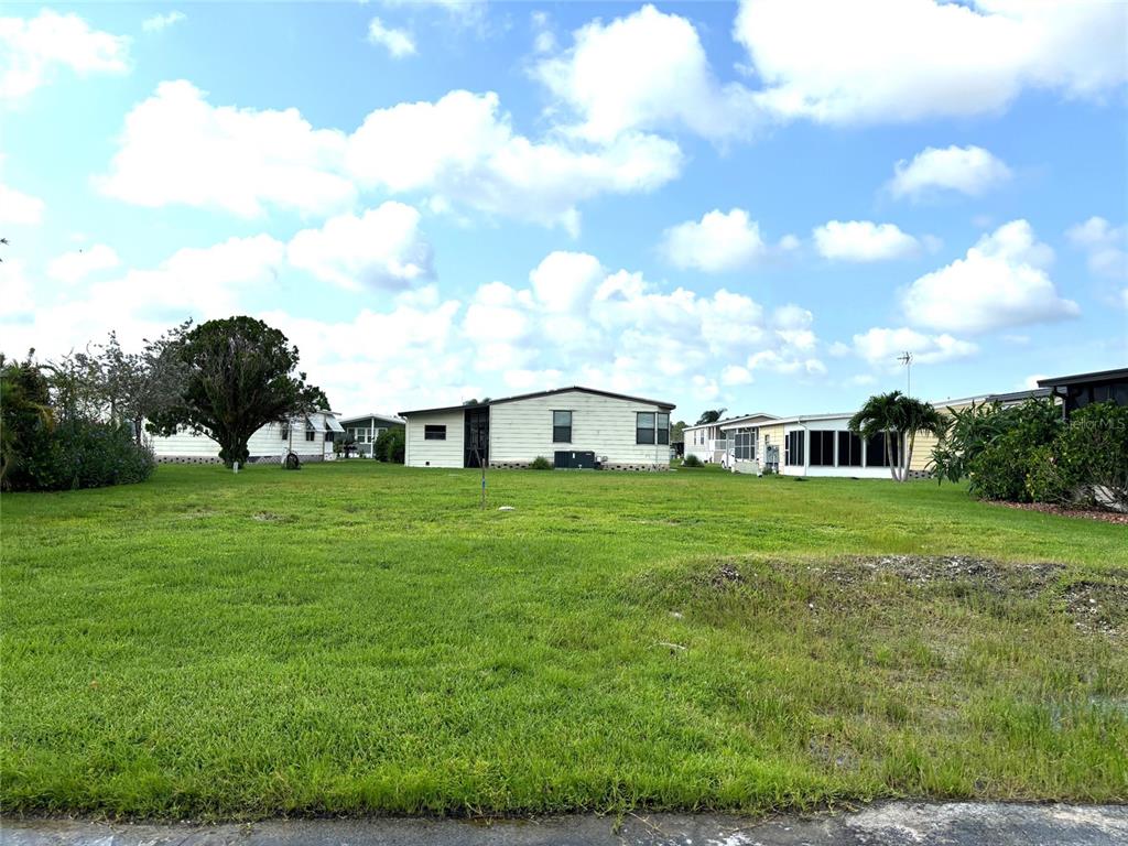 A grassy vacant lot sits in front of several manufactured homes under a cloudy sky — 404 TARDE LOGO CIRCLE, NORTH PORT, FL