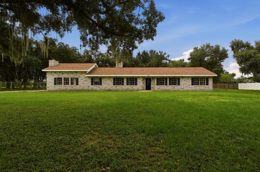 A single-story brick house with a brown shingled roof sits on a large grassy lawn — 2925 MCGEE ROAD, PLANT CITY, FL