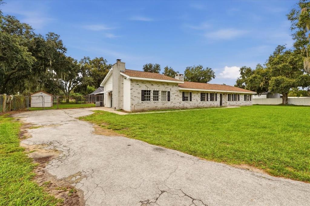 A single-story brick house with a cracked asphalt driveway and a detached shed — 2925 MCGEE ROAD, PLANT CITY, FL