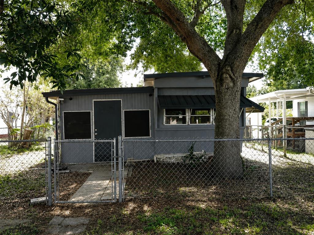A small gray house with a cross on the door and a chain-link fence — 6250 CONNECTICUT STREET, ZEPHYRHILLS, FL