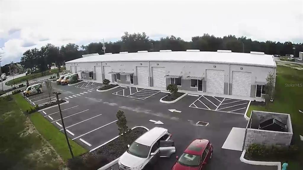 An aerial view shows a modern, single-story commercial warehouse building with a paved parking lot — 1550 TILESTON ROAD UNIT 108, ST CLOUD, FL