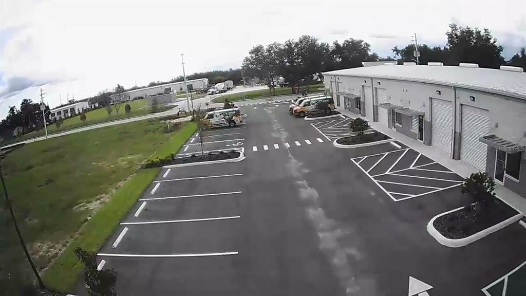 An aerial view shows a commercial building with a parking lot and adjacent grassy area — 1550 TILESTON ROAD UNIT 108, ST CLOUD, FL