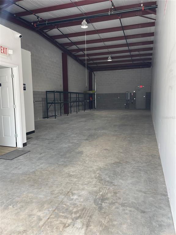 An empty industrial warehouse space features concrete block walls, a metal ceiling, and metal shelving — 1550 TILESTON ROAD UNIT 108, ST CLOUD, FL