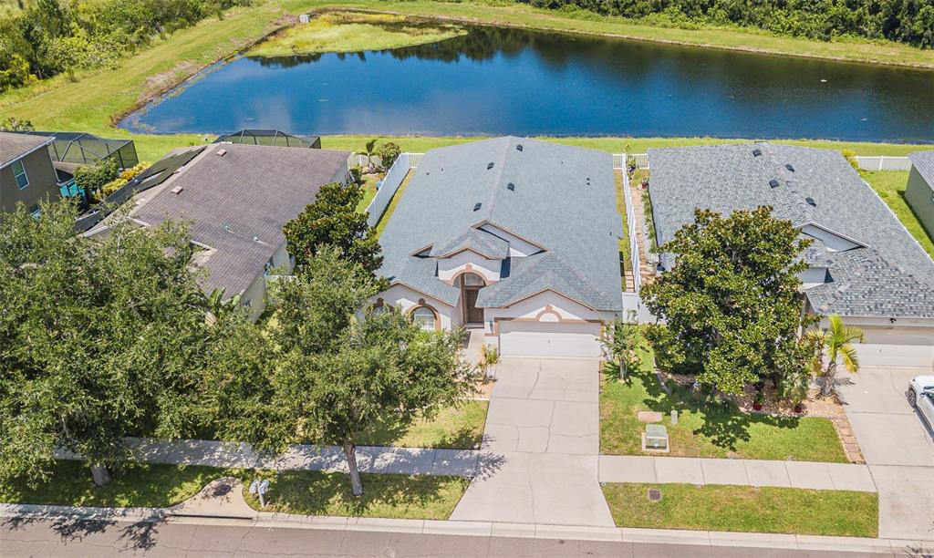An aerial view shows a suburban house with a gray roof and a backyard pond — 11345 FLORA SPRINGS DRIVE, RIVERVIEW, FL