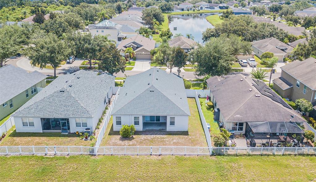 An aerial view shows the backyards and rear exteriors of three suburban houses with fences — 11345 FLORA SPRINGS DRIVE, RIVERVIEW, FL