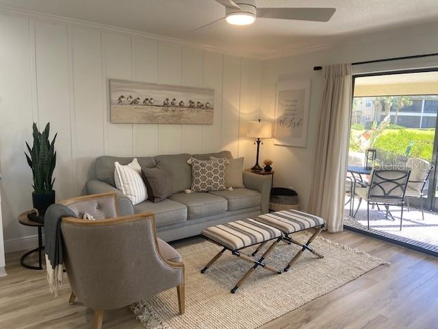 A living room features a gray sofa, a patterned armchair, and a sliding glass door — 646 YARDARM DRIVE UNIT 23, APOLLO BEACH, FL