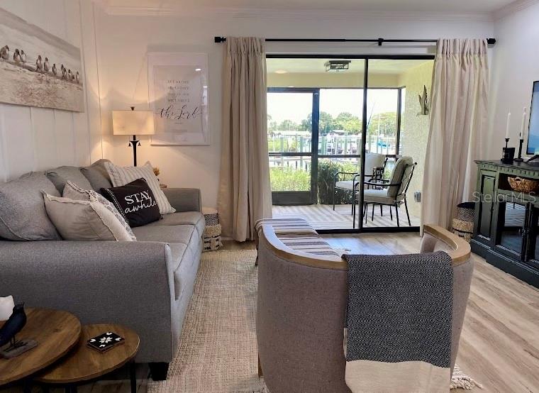 A living room features a grey sofa, an armchair, and a sliding door to a balcony — 646 YARDARM DRIVE UNIT 23, APOLLO BEACH, FL