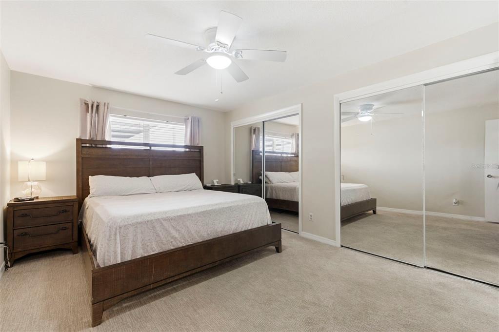 A bedroom features a wooden bed frame, carpeted flooring, and large mirrored closet doors — 3022 JACKSON DRIVE, HOLIDAY, FL
