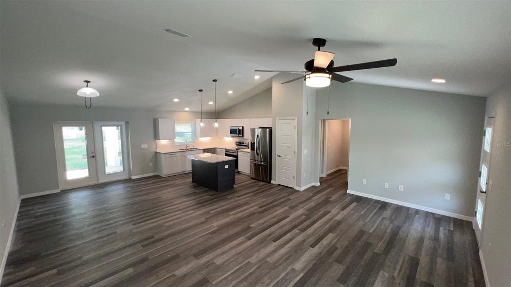 An open-concept kitchen and living area features wood-look flooring, white cabinetry, and a center island — TBD BAY DRIVE PASS, OCKLAWAHA, FL