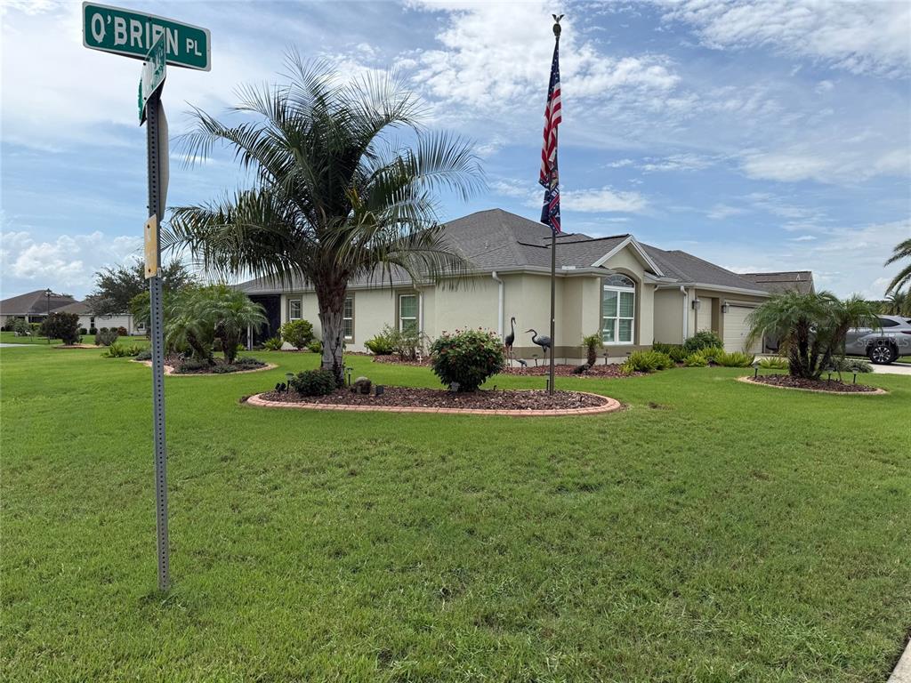 A single-story house with a lawn, palm trees, and an American flag on a pole — 3578 OBRIEN PLACE, THE VILLAGES, FL