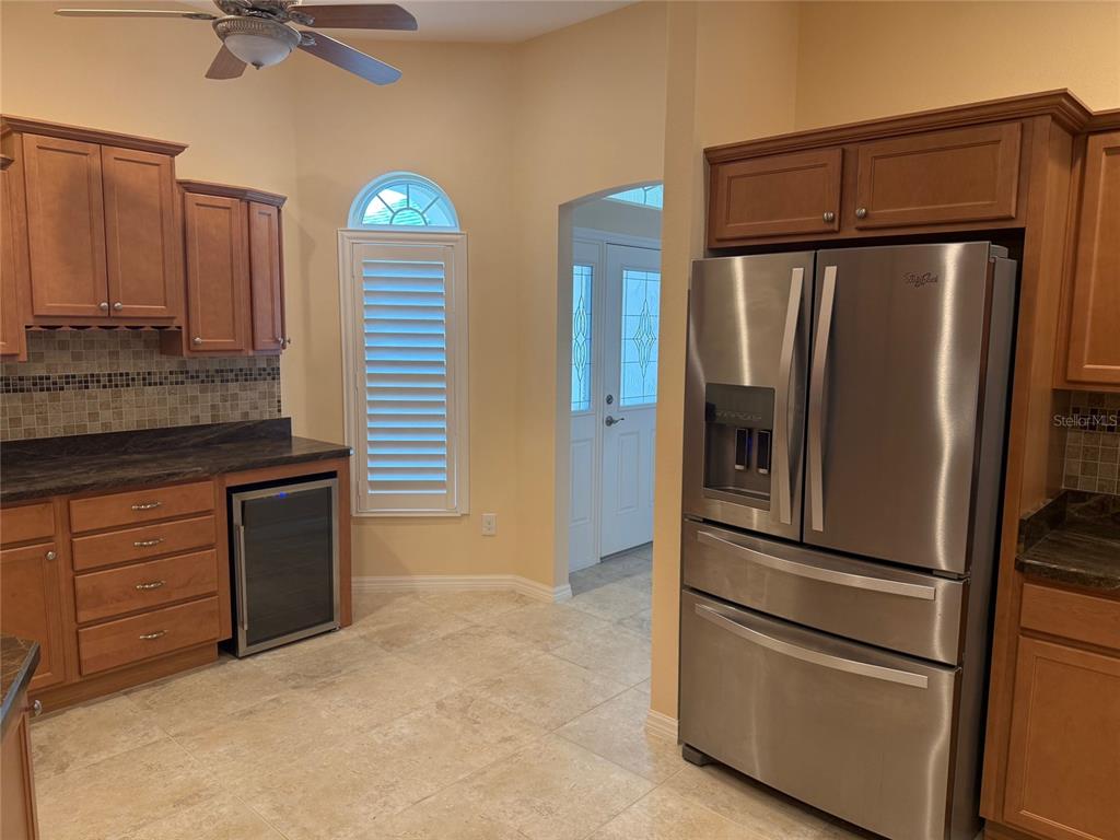 A kitchen featuring wood cabinets, stainless steel appliances, a wine cooler, and tile flooring — 3578 OBRIEN PLACE, THE VILLAGES, FL