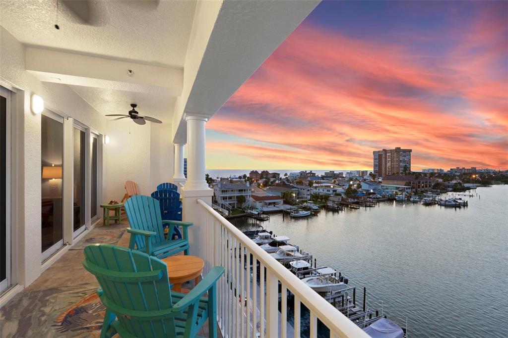 An aerial view shows a multi-story apartment building with a parking lot and sunset sky — 17717 GULF BOULEVARD UNIT 604, REDINGTON SHORES, FL